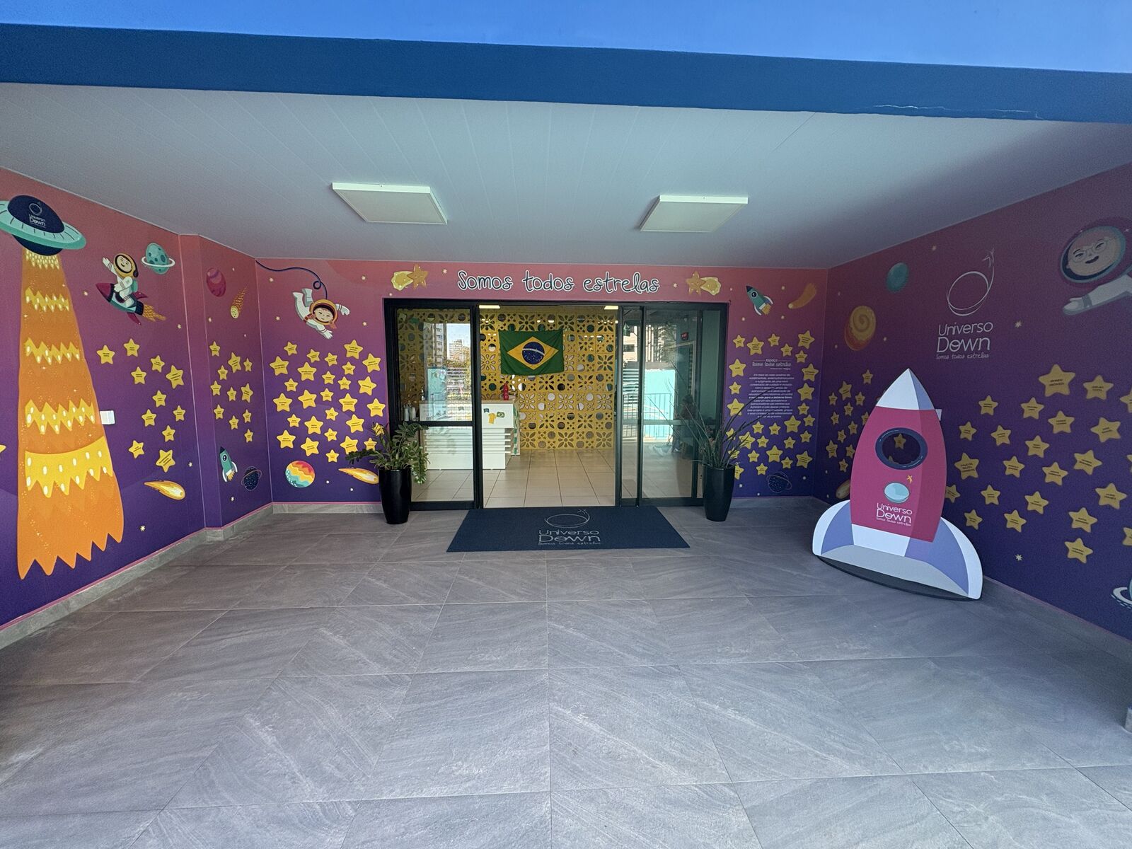 Entrada do Universo Down, com paredes ilustradas de estrelas e a frase Somos todos estrelas